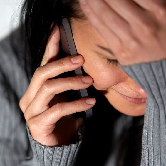 people, helpline and domestic violence concept - close up of unhappy woman crying and calling on smartphone